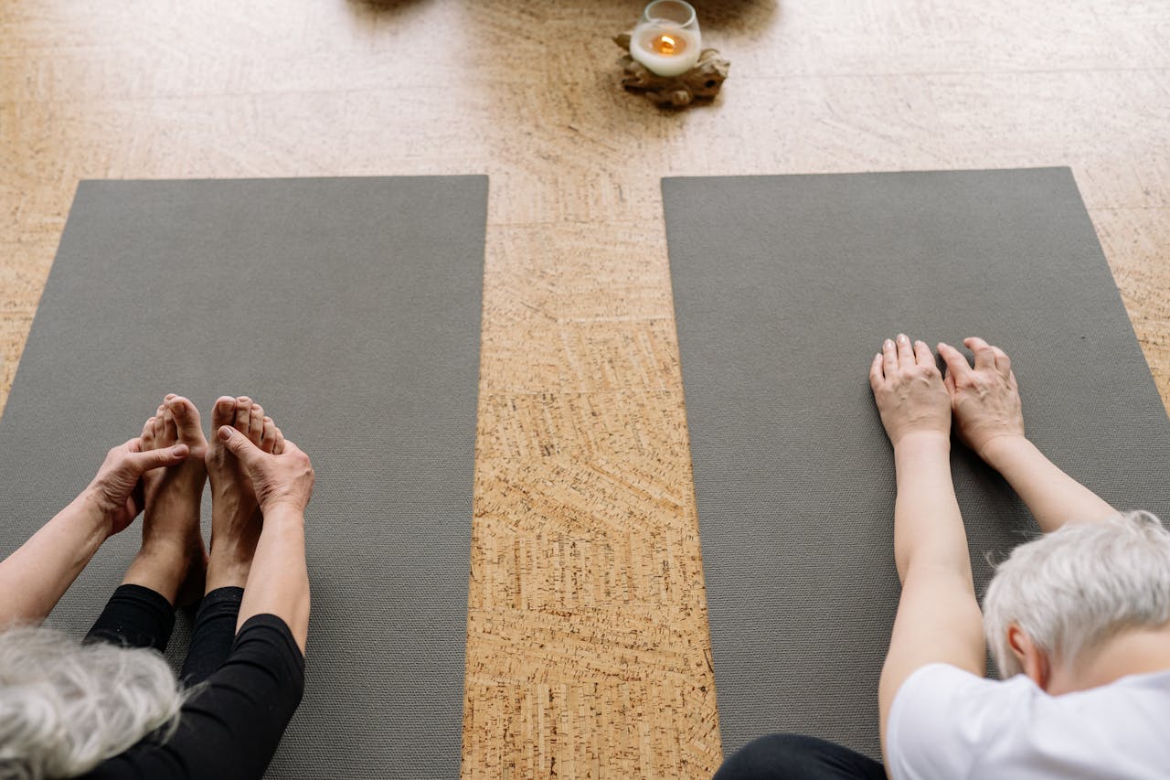 Two senior adults practicing yoga indoors, focusing on relaxation and flexibility.
